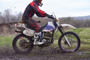 Extreme racing in rural area with side view of sportsman sitting on motorbike